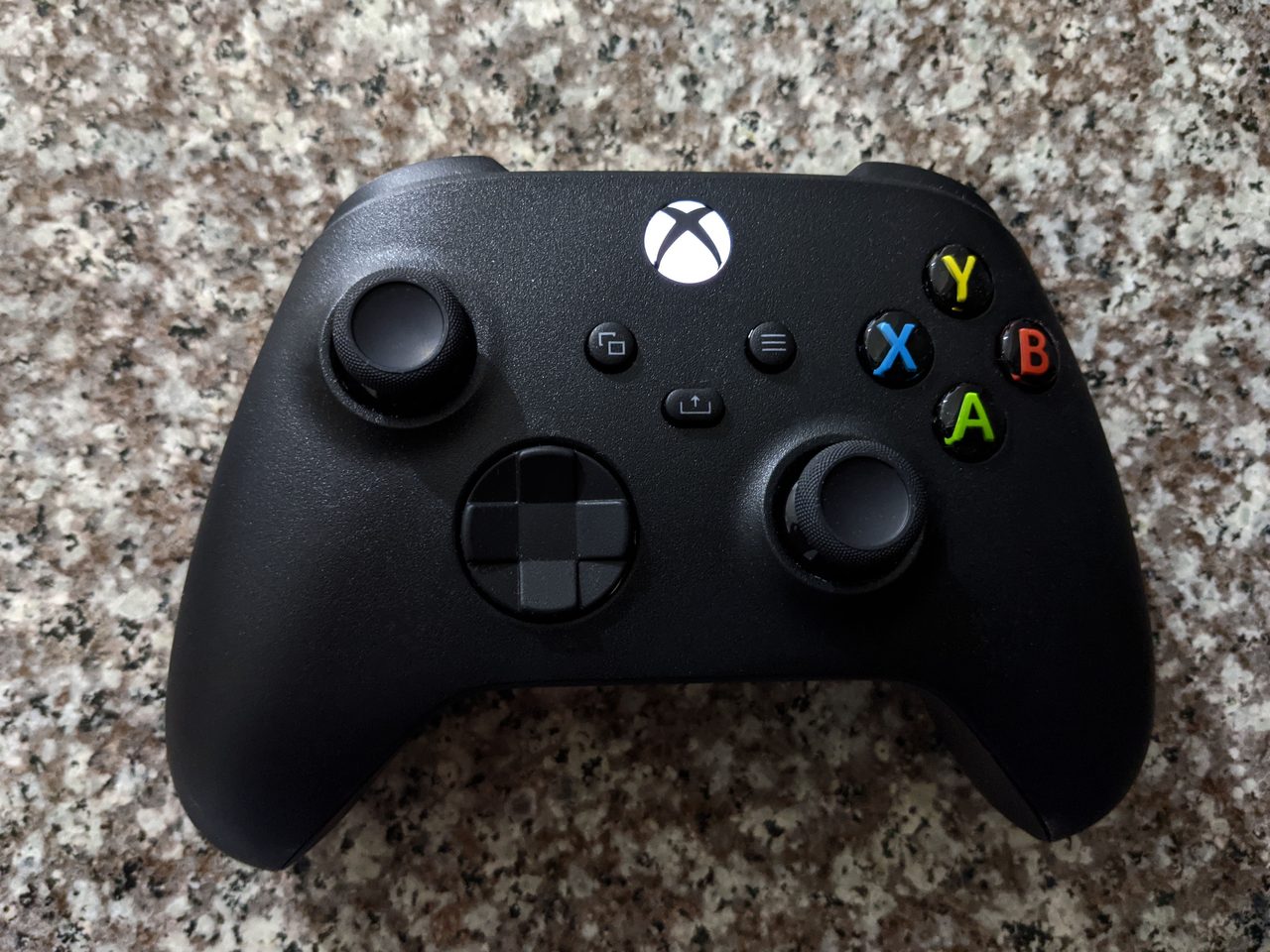 An Xbox Series X controller in carbon black photographed close-up, showing its analog thumbsticks, D-pad and face buttons.